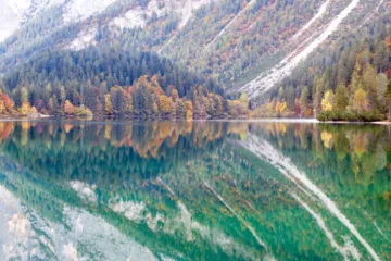 Vista autunnale del Lago di Tovel con riflessi d'acqua e alberi colorati, Val di Non, Trentino