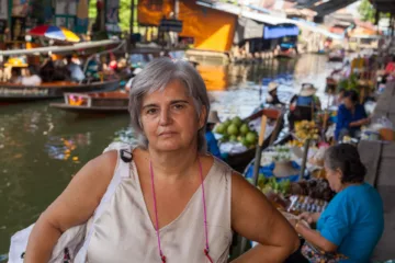 Mia moglie al Mercato Flottante di Damnoen Saduak in Thailandia, circondata da barche e venditori locali.