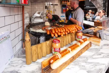 Bancarella di street food che cucina e vende salsicce alla griglia con pane e crauti al mercato di Camden Town, Londra.