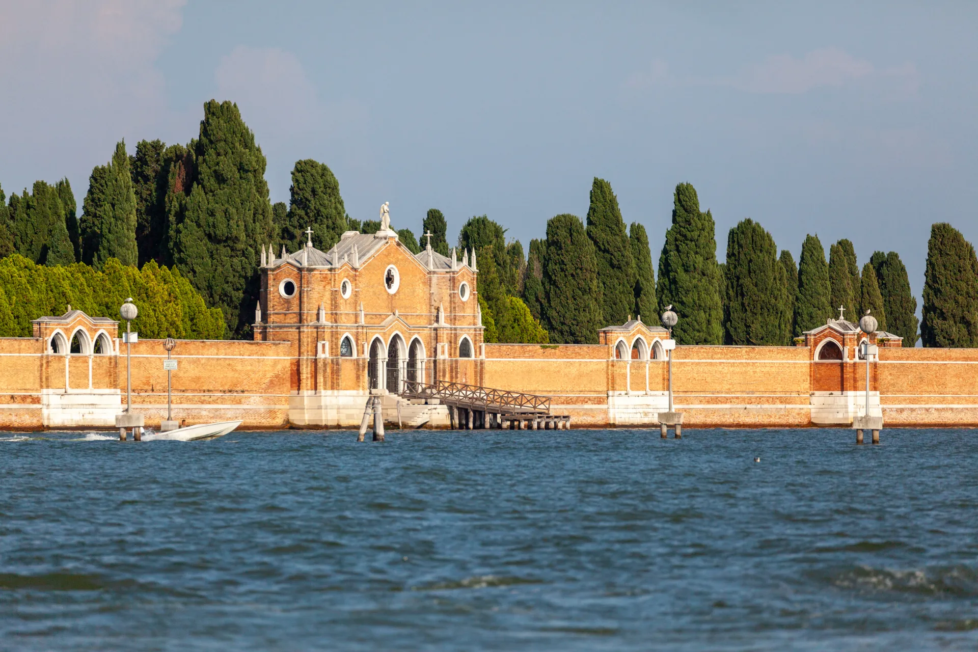 Ingresso del Cimitero di San Michele a Venezia visto dall'acqua, con cipressi sullo sfondo.