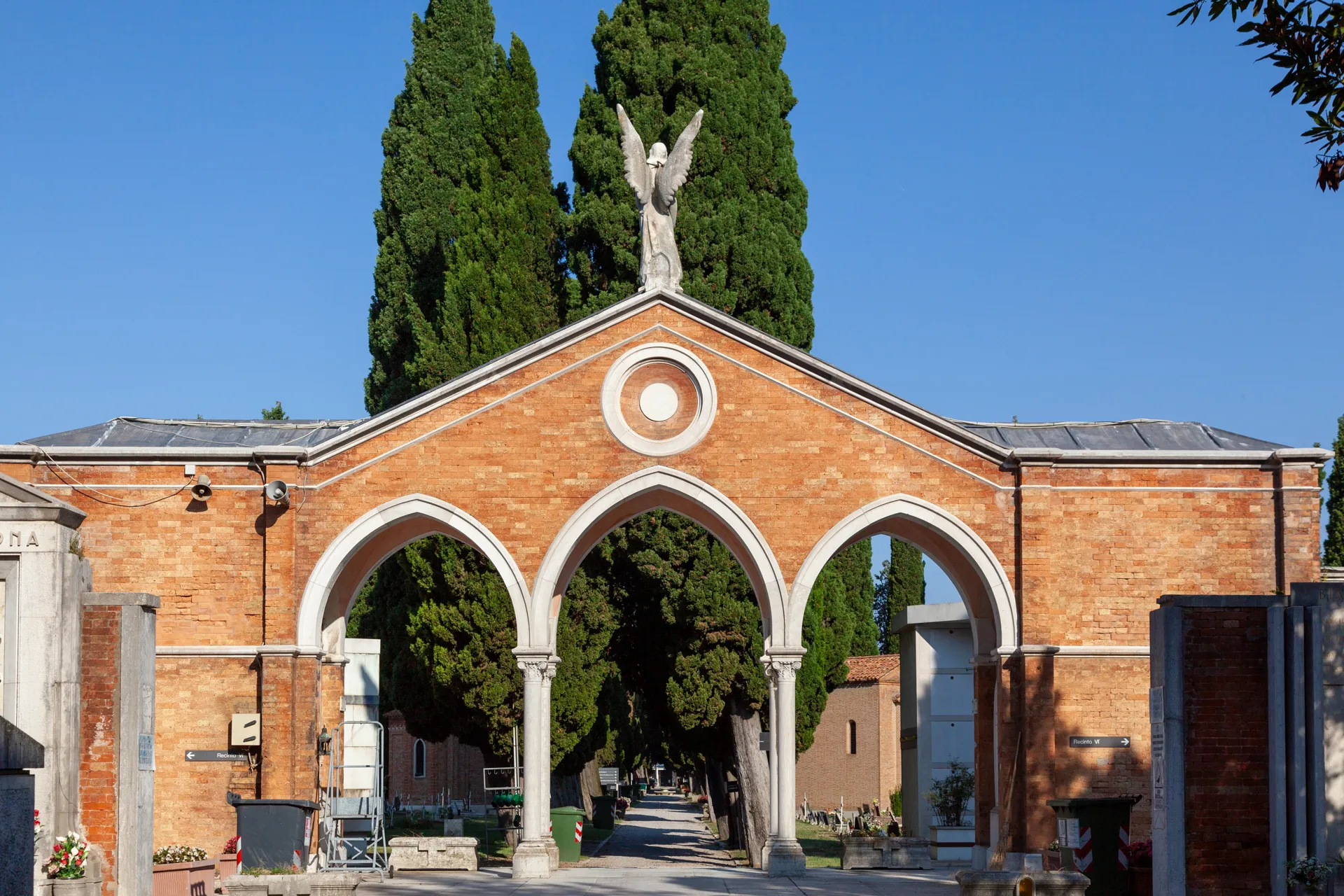 Vista frontale dell'ingresso principale del cimitero di San Michele a Venezia con colonne e alberi sullo sfondo