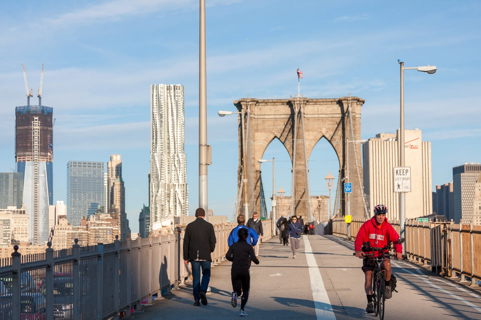 Pedoni e ciclisti camminano e pedalano sulla passerella del Ponte di Brooklyn a New York.