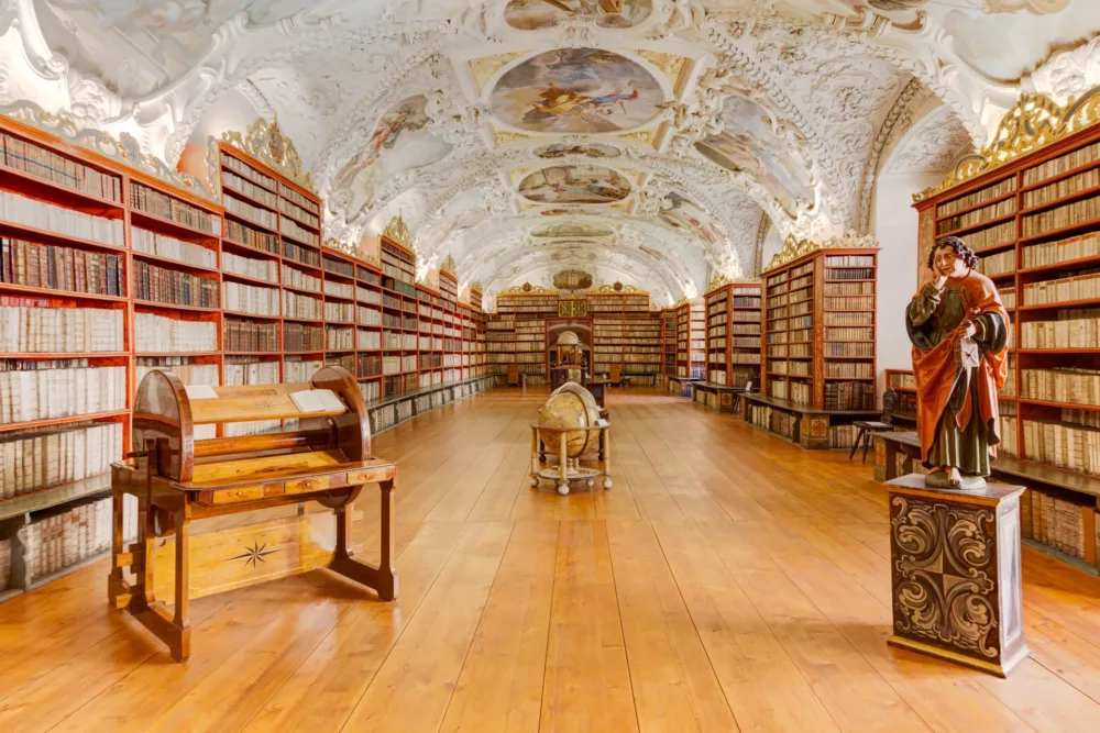 Sala Teologica della Biblioteca del Monastero di Strahov a Praga, con soffitti affrescati e scaffali pieni di antichi libri.