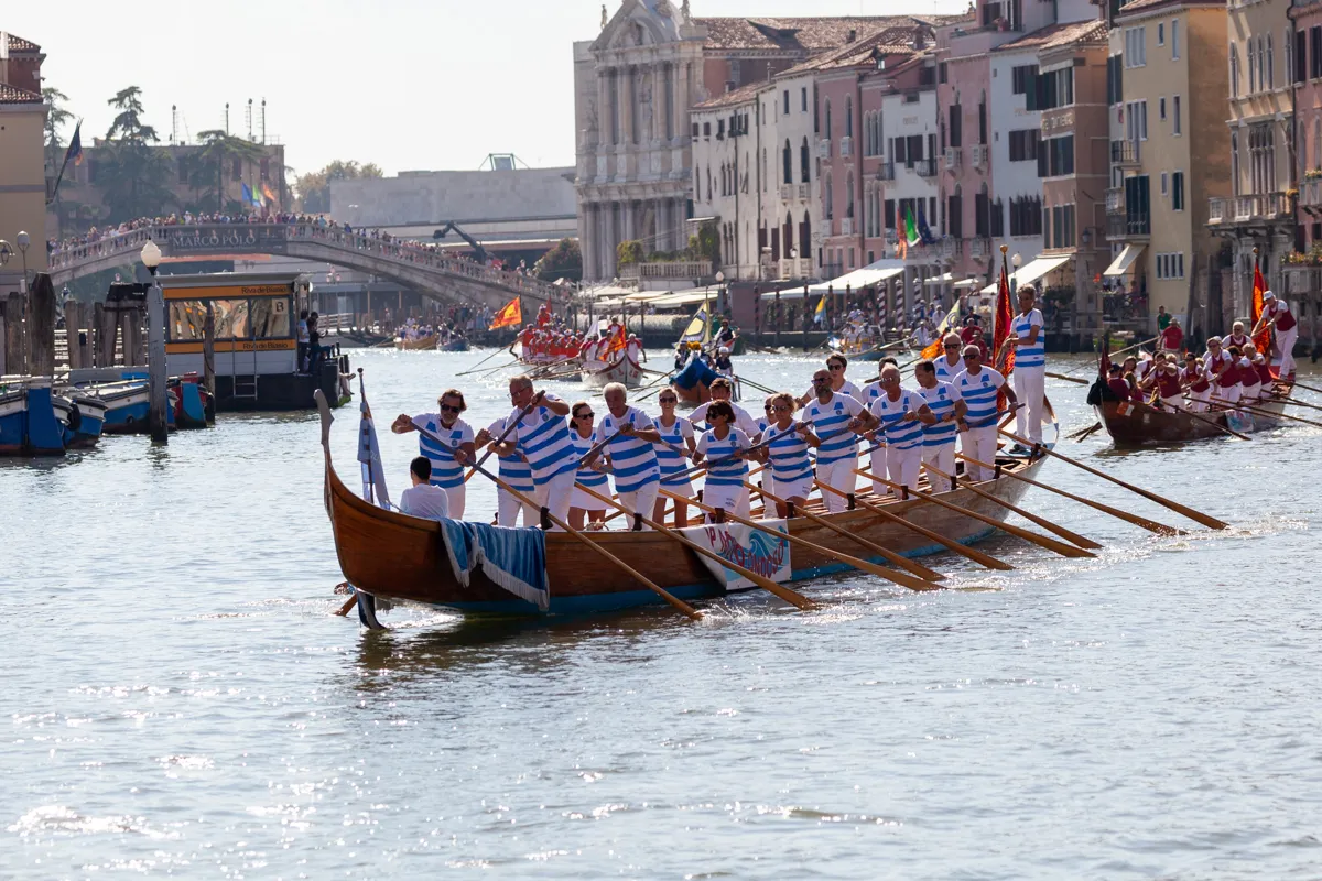 Rematori in abiti tradizionali blu e bianchi alla Regata Storica 2024.