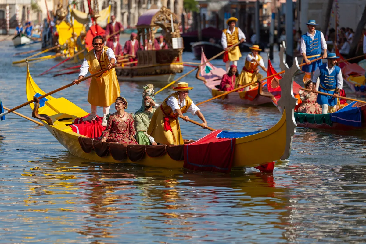 Imbarcazione gialla con vogatori in costumi storici durante la Regata Storica di Venezia