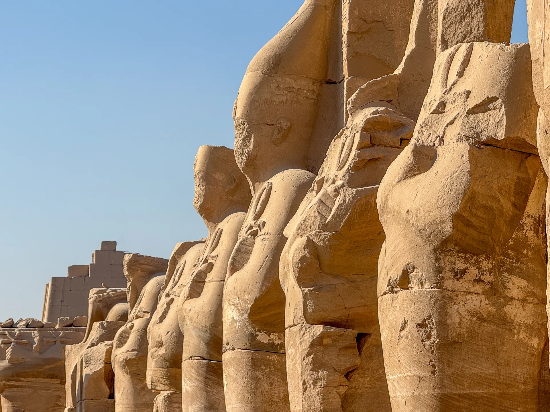 File di statue colossali erose dal tempo nel Tempio di Karnak, Luxor.