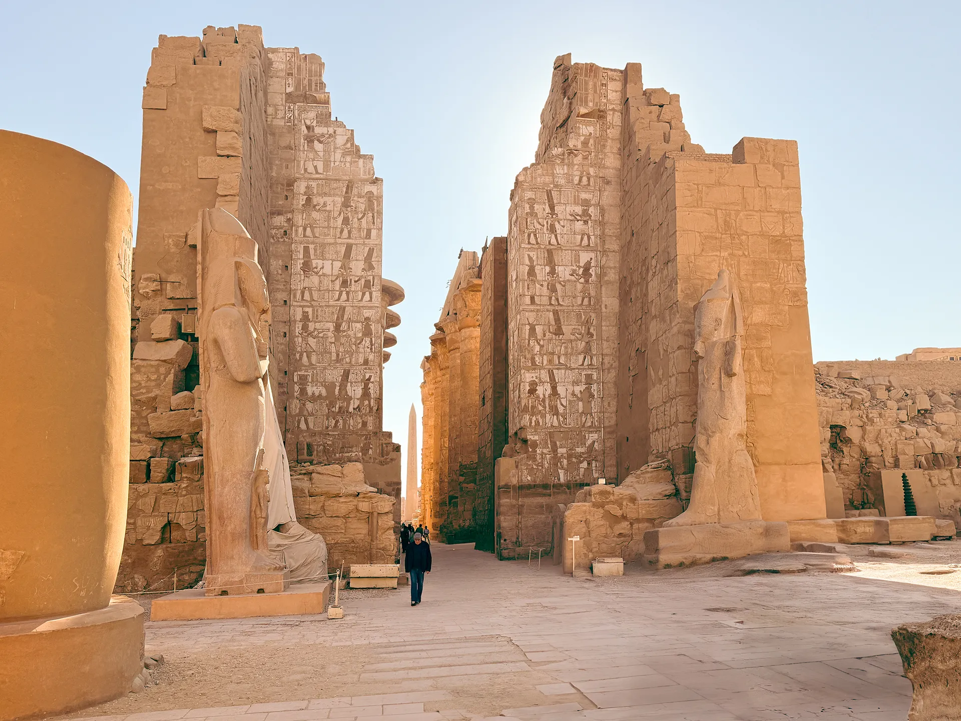 Ingresso monumentale del Tempio di Karnak a Luxor, Egitto, con statue colossali e geroglifici incisi sulle mura, illuminati dalla luce del mattino.