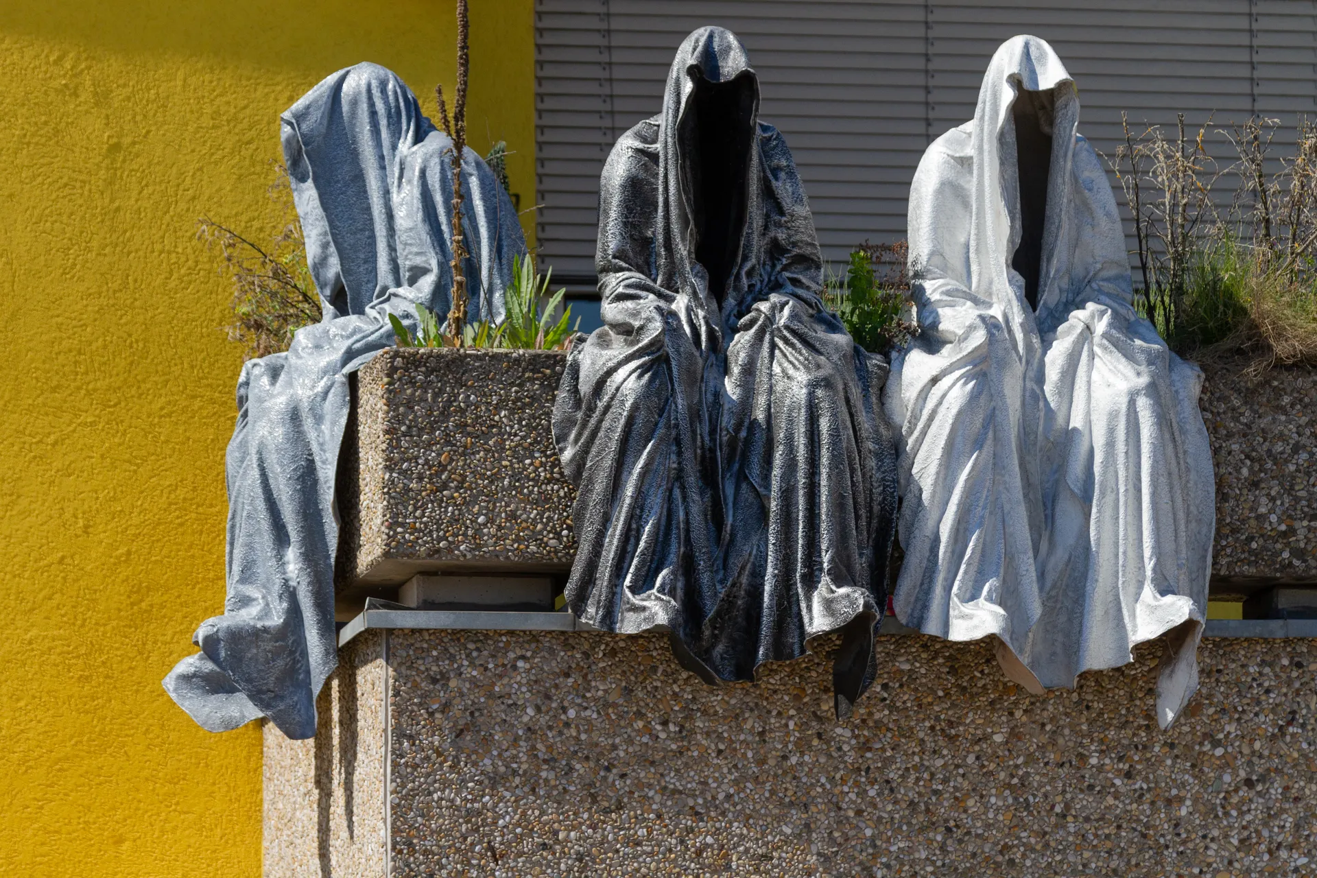 Tre figure incappucciate in una scultura urbana a Linz.