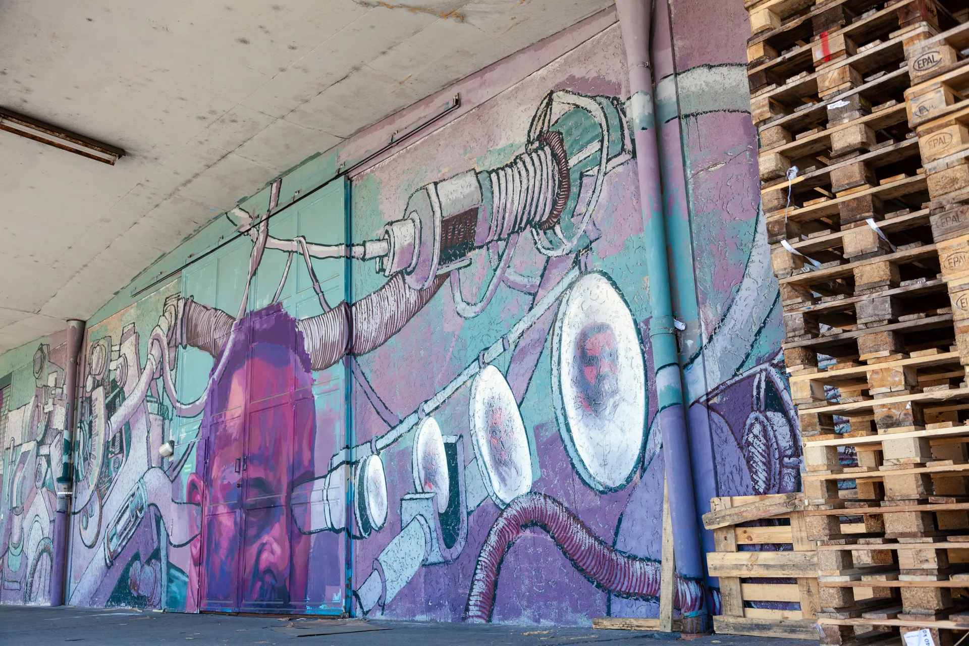 Murales stilizzato con figure umane su un edificio industriale a Linz.