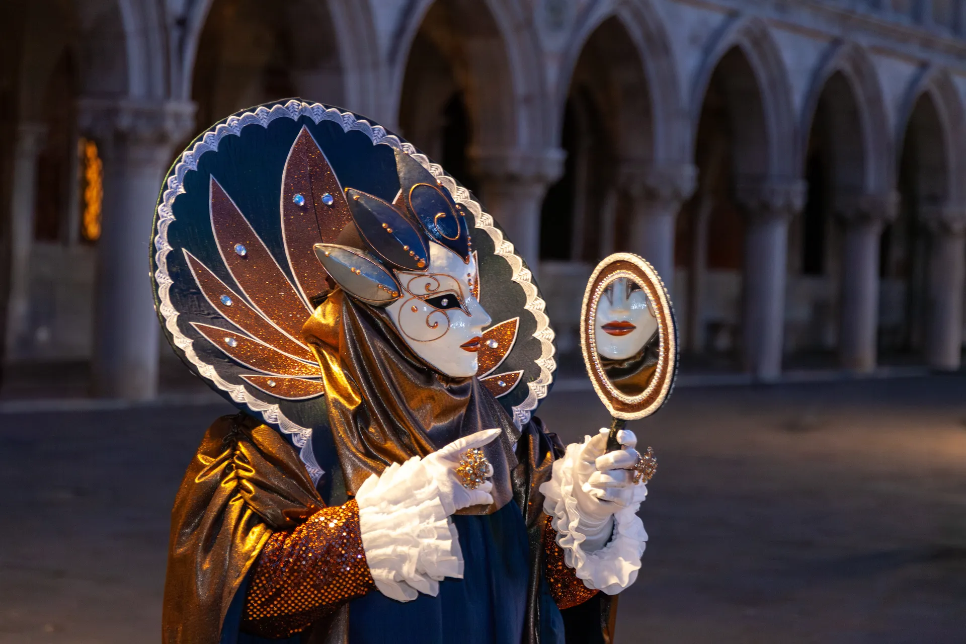 Foto scattata durante l'ora blu del Carnevale di Venezia 2025, con una maschera raffinata che si specchia tra le arcate del Palazzo Ducale.