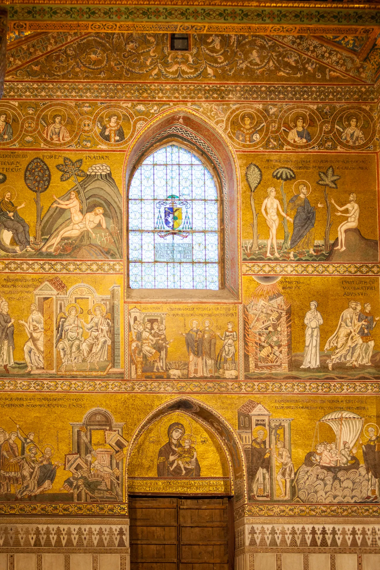 Parete con mosaici biblici e vetrata centrale nel Duomo di Monreale