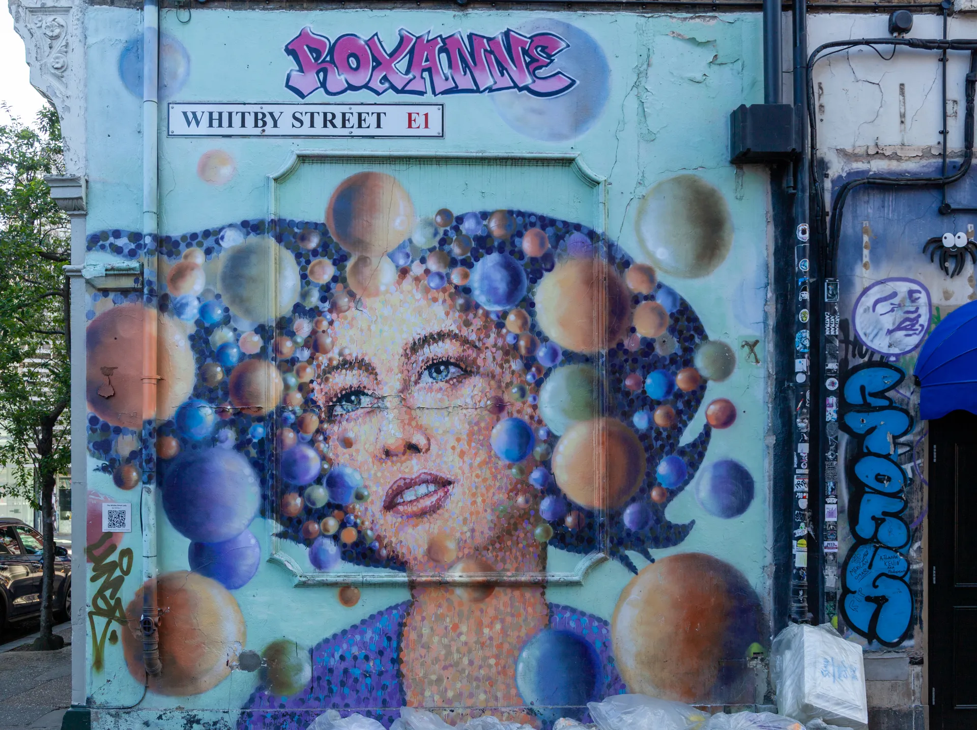 Un volto sognante circondato da mondi colorati. Whitby Street, Shoreditch