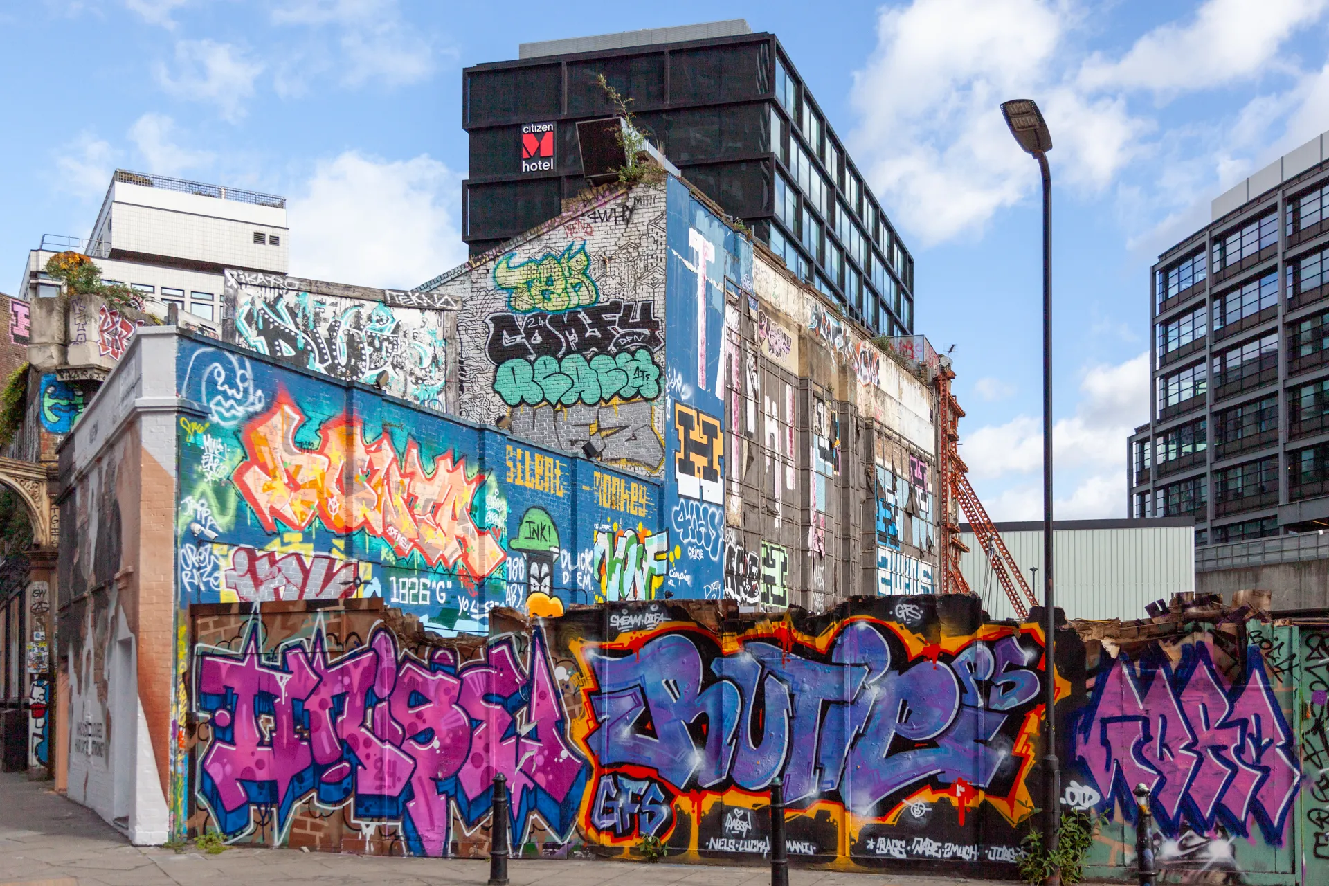 Street art esplosiva a Shoreditch, Londra, con il CitizenM Hotel sullo sfondo. Holywell Lane, Shoreditch