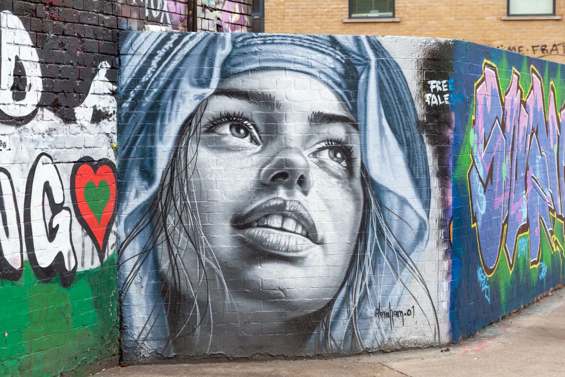 Speranza e intensità nello sguardo della donna dipinta da Abraham.OJ. Brick Lane Yard, adiacente a Pedley Street