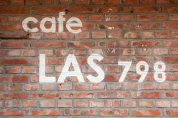 Scritta bianca 'cafe LAS 798' su muro di mattoni rossi
