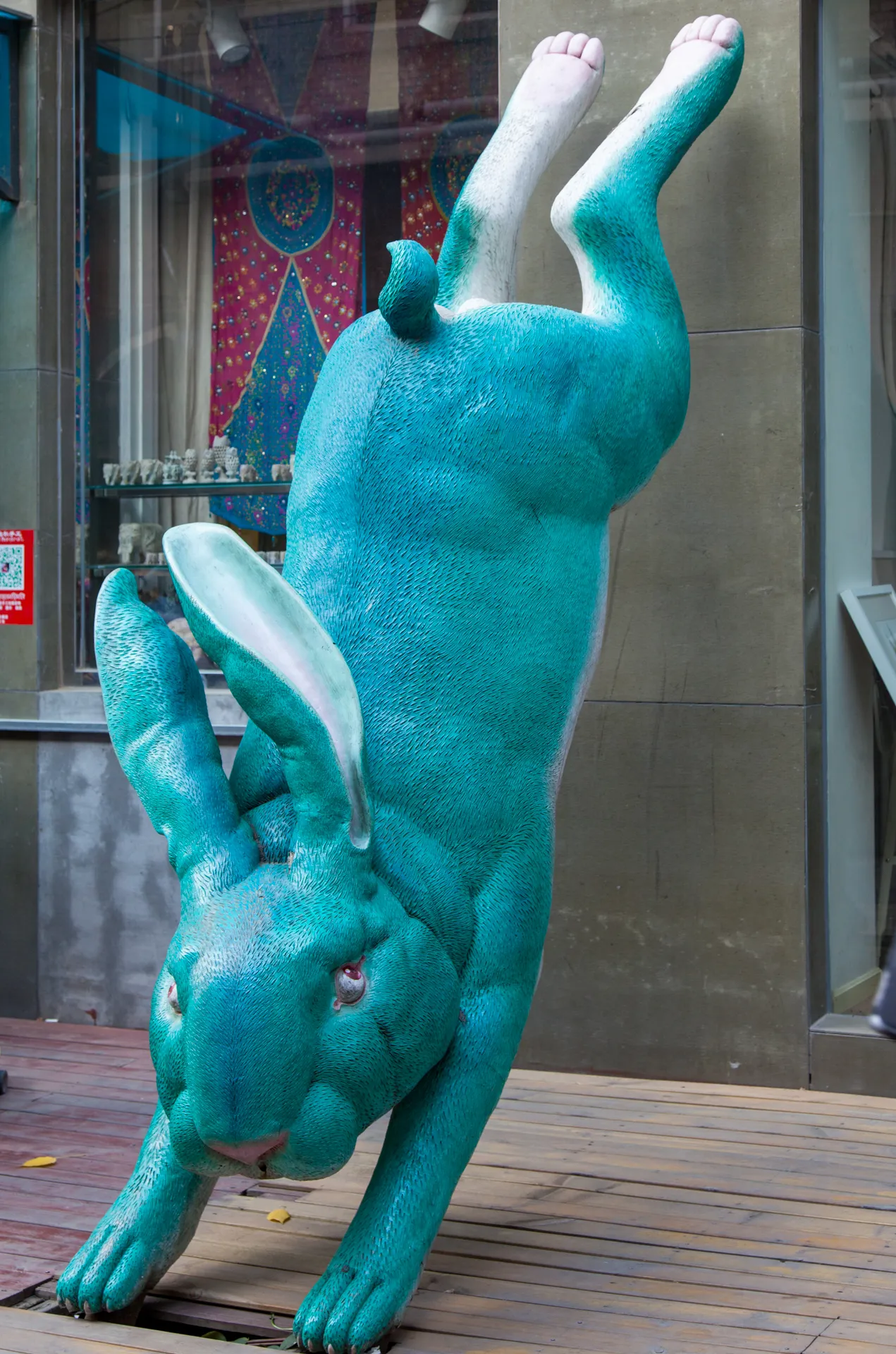 Grande scultura di coniglio turchese che poggia sulla testa