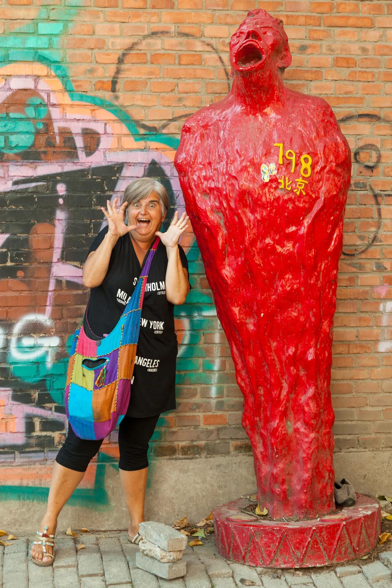 Donna posa imitando una scultura rossa urlante