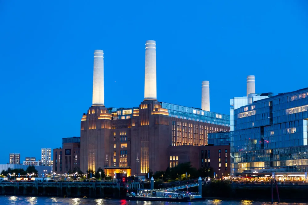 Battersea Power Station Londra illuminata all’ora blu vista da Grosvenor Road con luci riflesse sul Tamigi