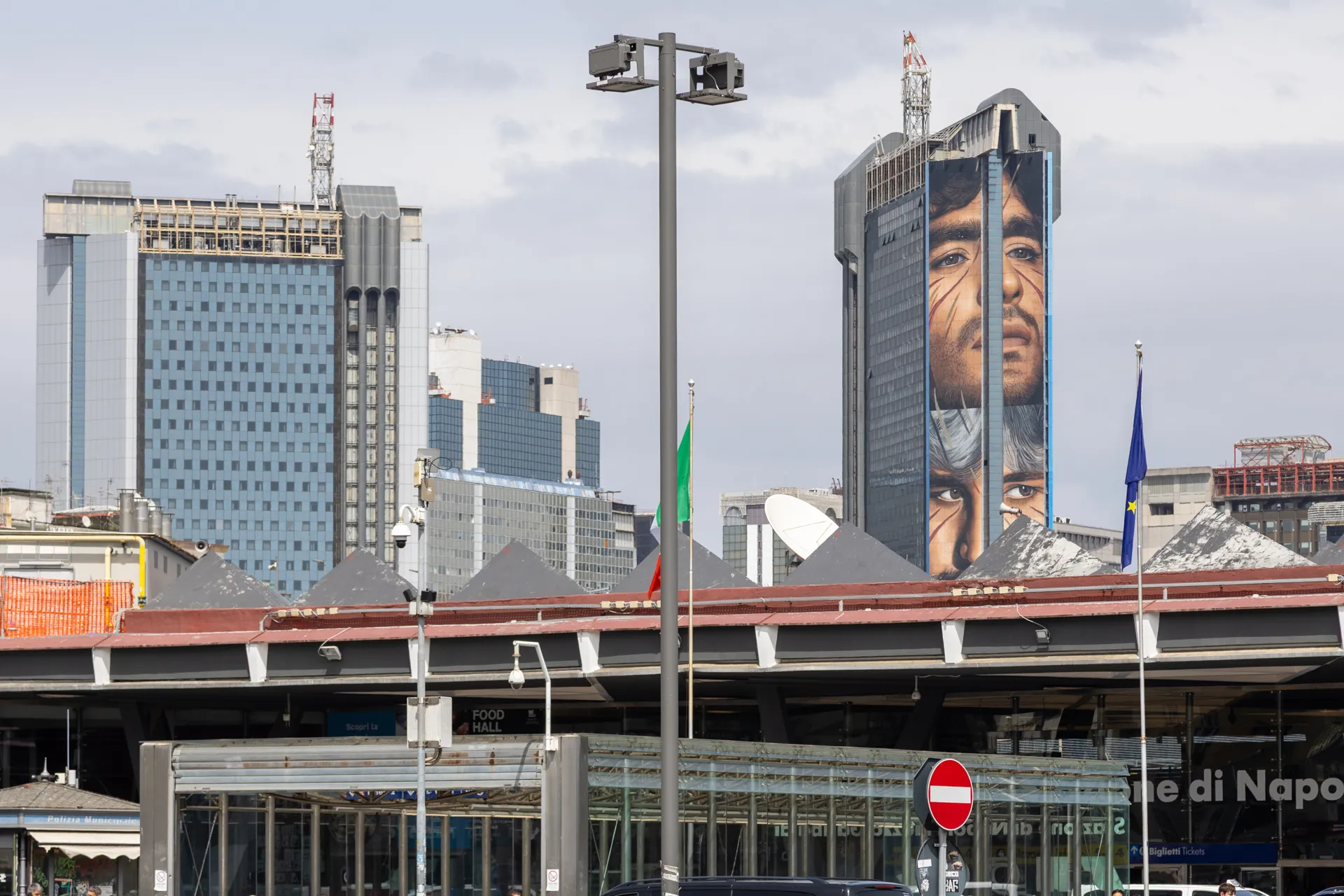 Grande murale visibile tra gli edifici moderni di Napoli