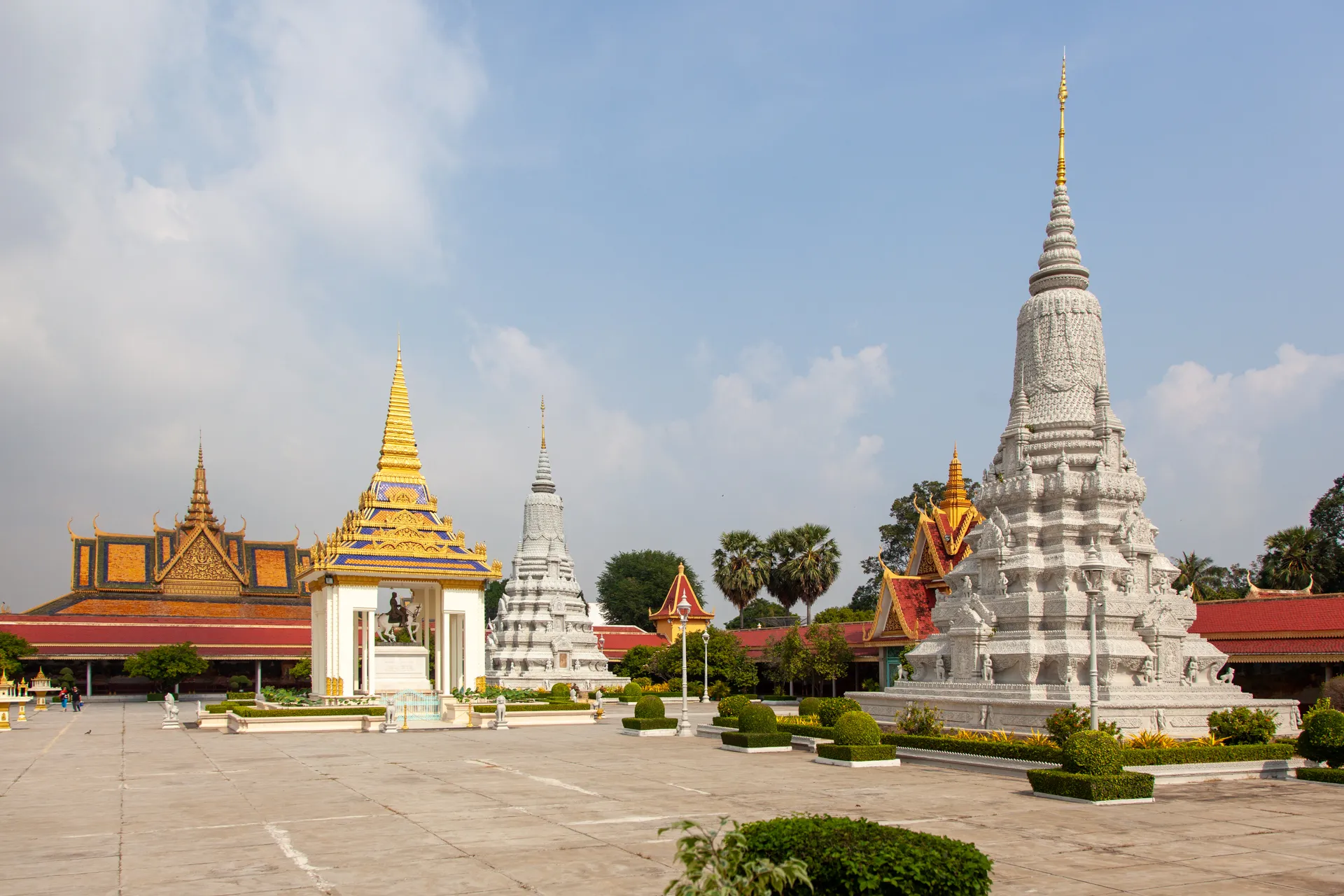 Cortile del Palazzo Reale di Phnom Penh con stupa bianca, tetti dorati e architetture cambogiane.